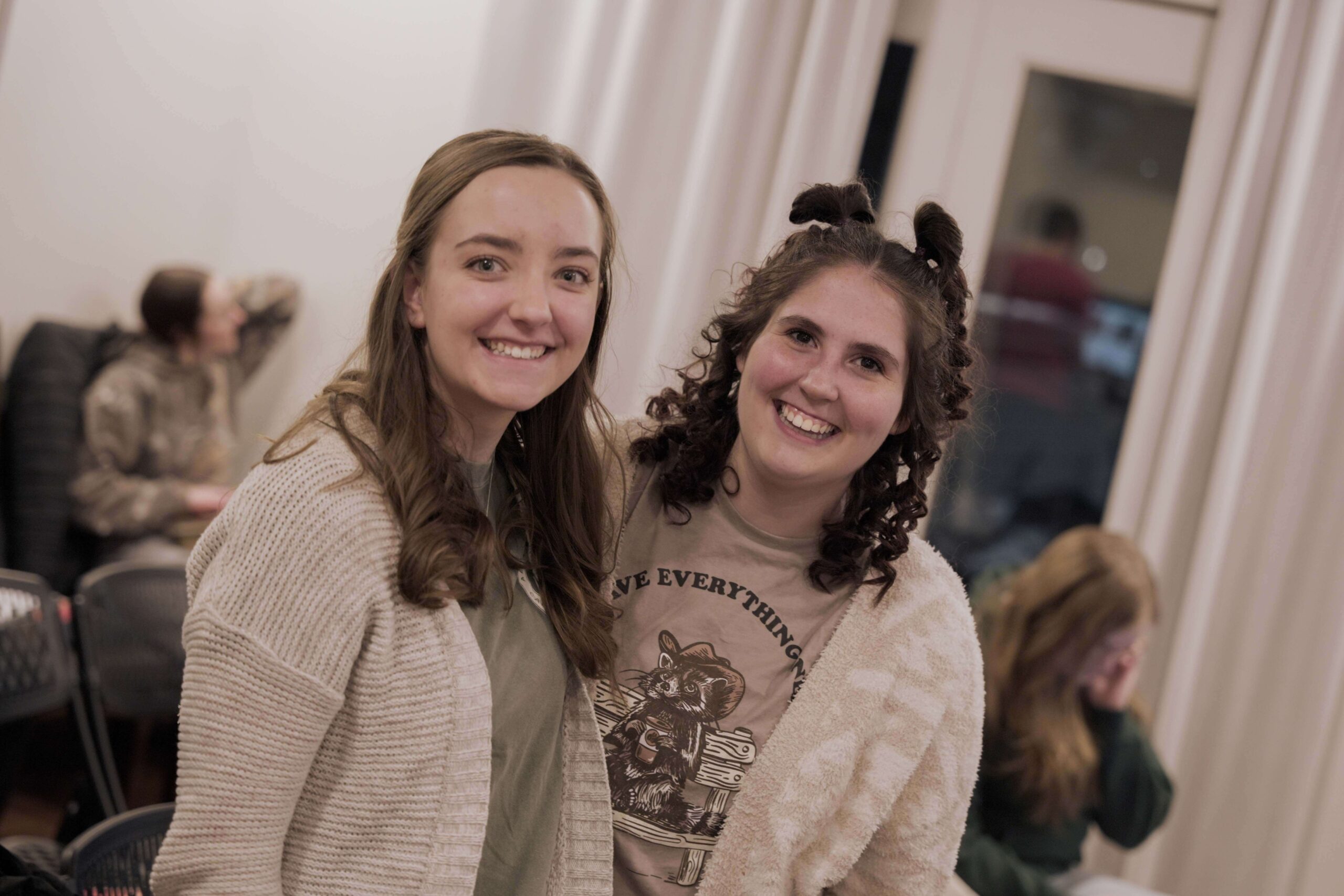 Two girls smiling in matching white cardigans